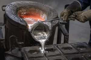 Arbeiter, der geschmolzenes Aluminium in Gussformen gießt