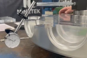 A dial indicator checking a machined metal part during dimensional inspection.