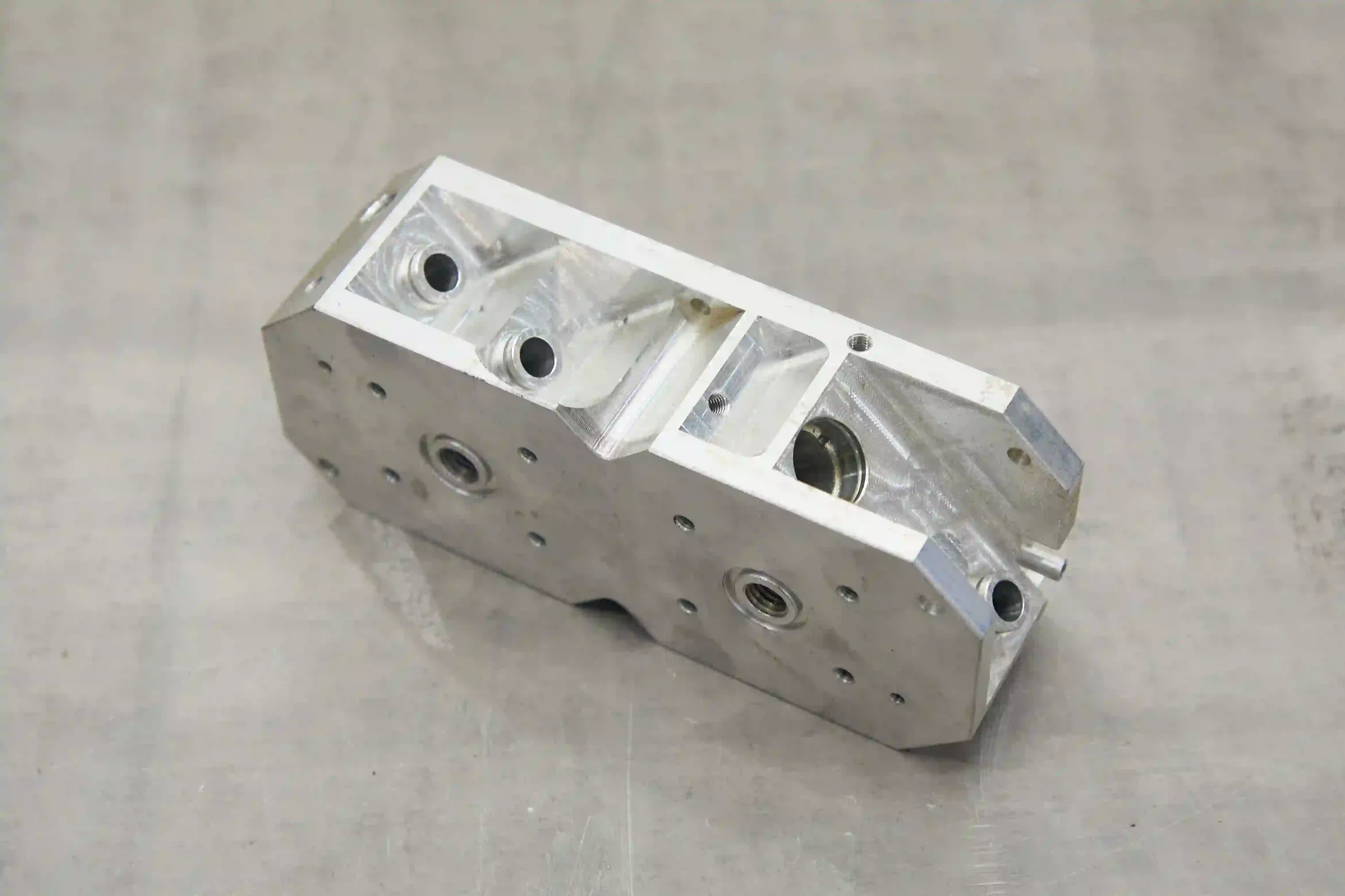 Rectangular magnesium alloy housing with precision-machined holes, internal cavities, and mounting features.
